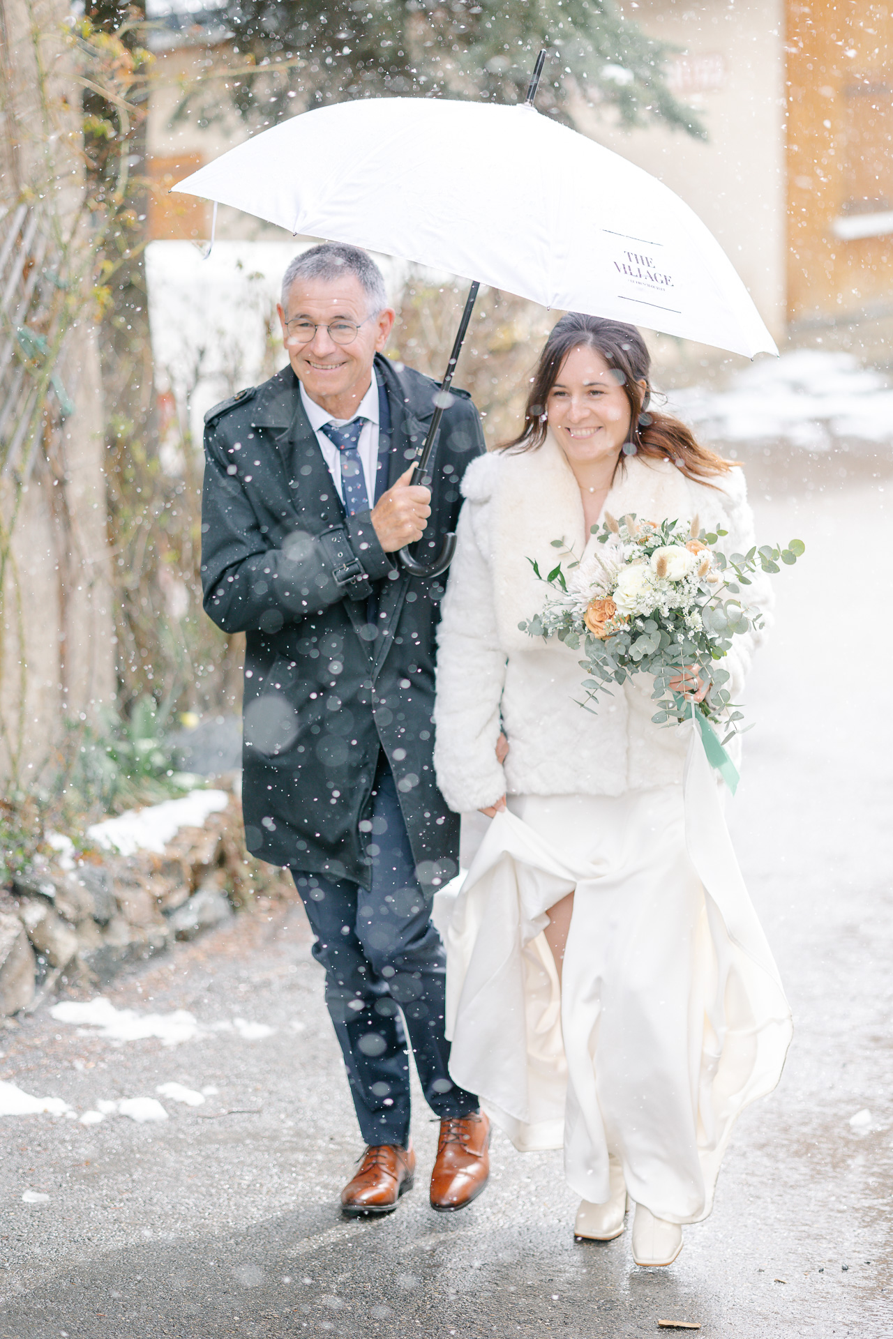 La marié avance s'avance au bras de son père sous la neige