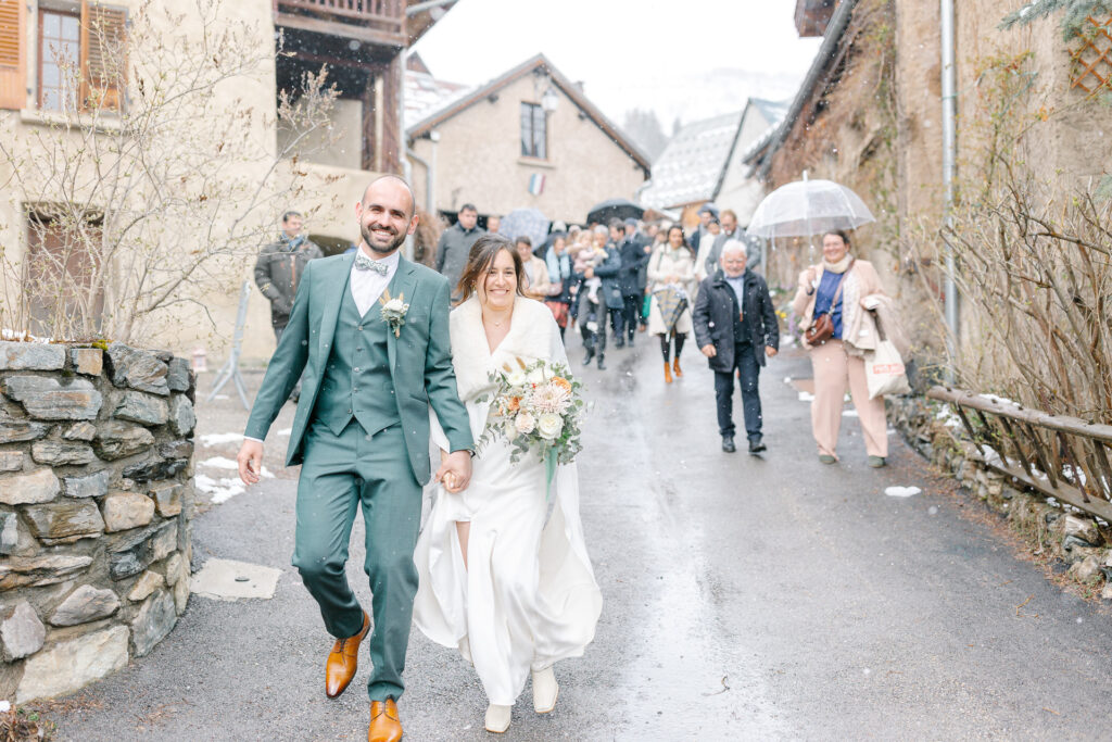 Les mariés marchent dans la rue suivis de leurs invités