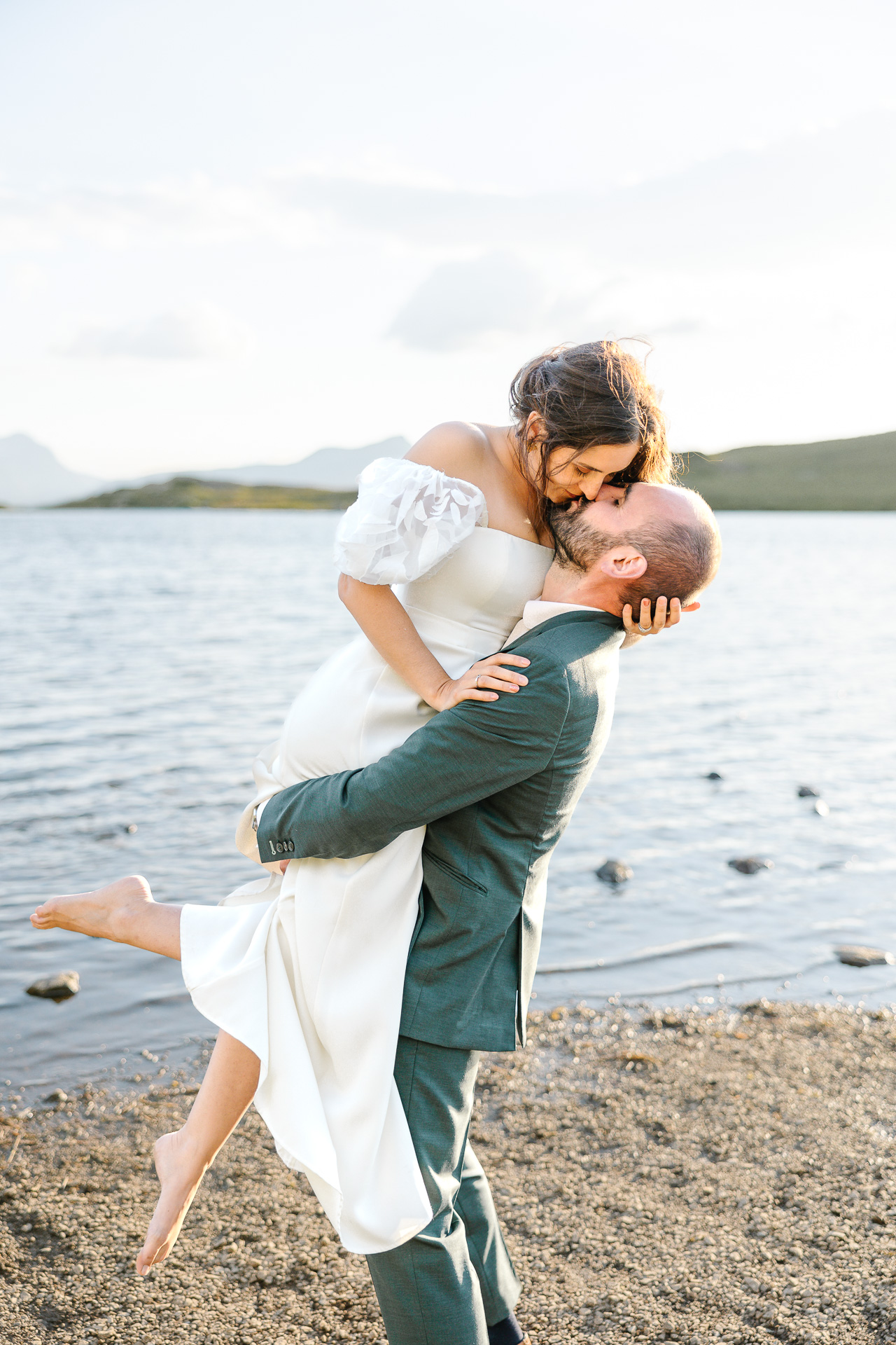 Le marié porte la mariée au bord d'un lac à l'alpes d'huez